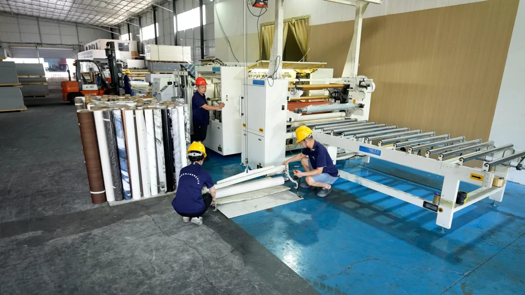Workers operating the wall panel laminating machine